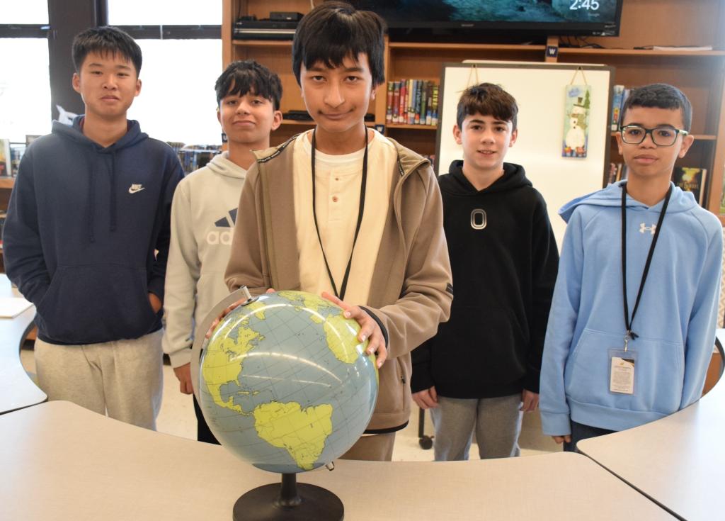 five students stand together with one holding a globe